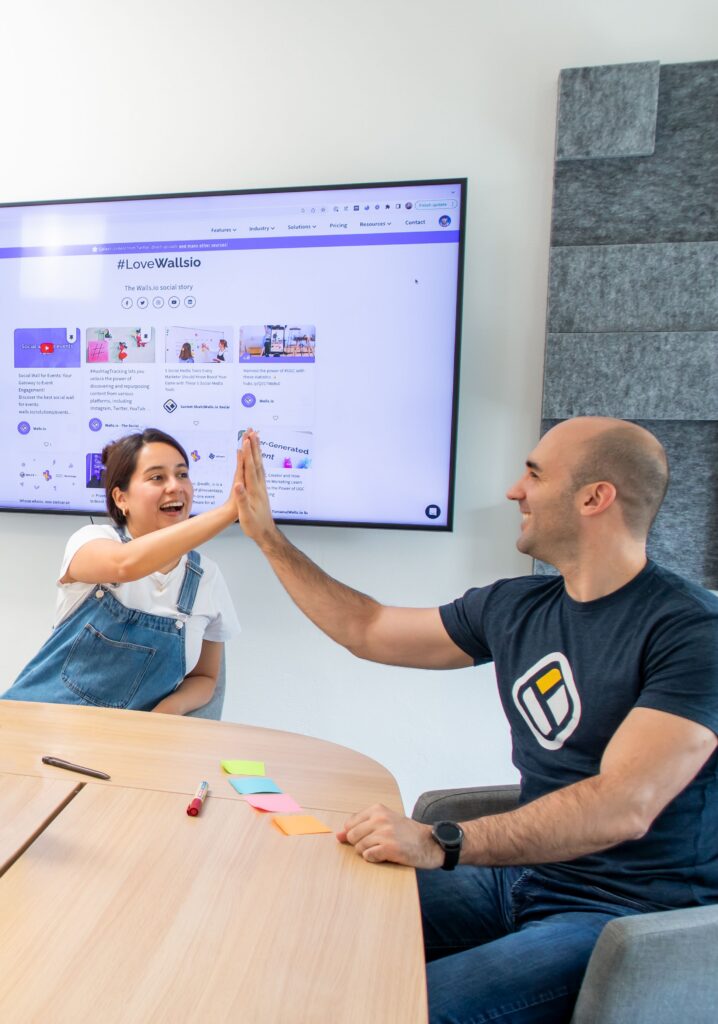 Two coworkers celebrating a successful collaboration with a high-five in a modern office environment.